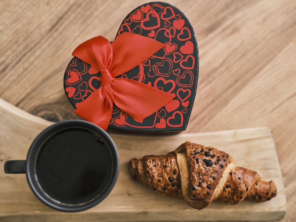 a heart shaped box of cookies next to a cup of coffee