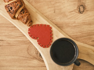 a cup of coffee and a piece of bread on a wooden spoon