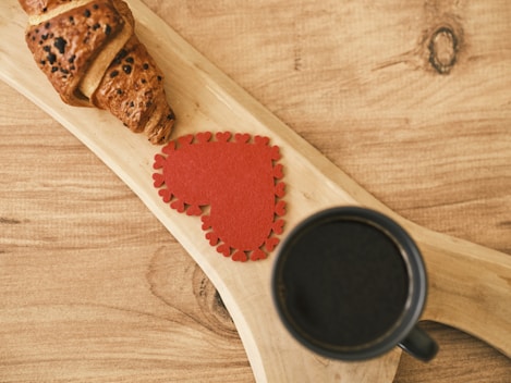 a cup of coffee and a piece of bread on a wooden spoon