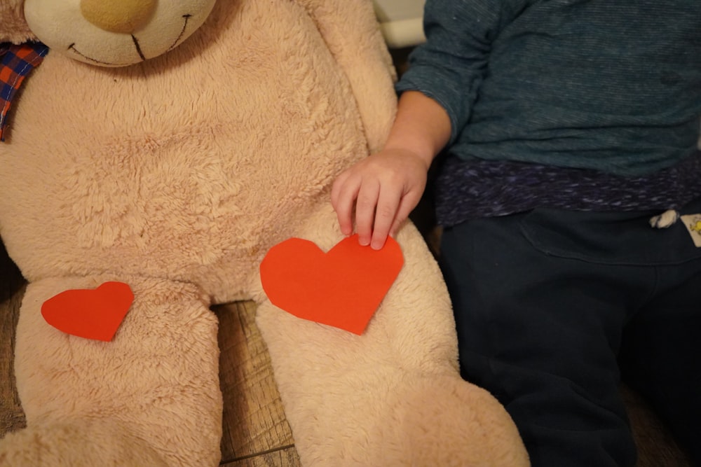 a child holding a teddy bear with two hearts on it