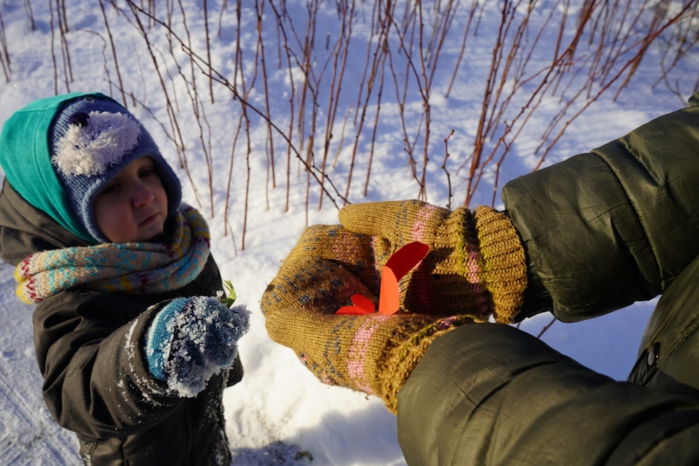 a person holding a child's hand in the snow