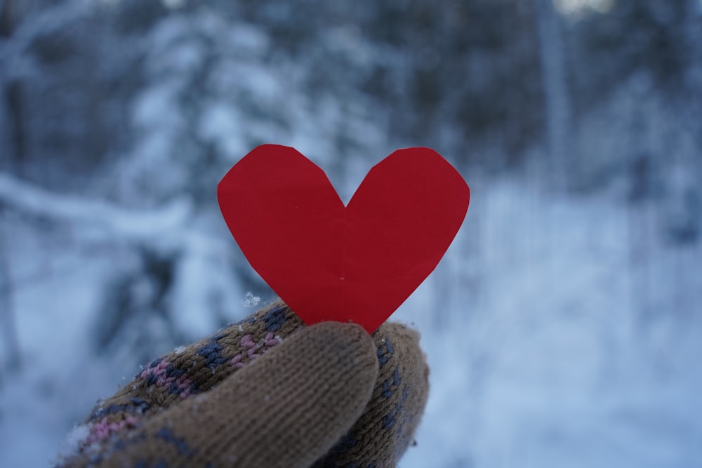 a person's hand holding a red paper heart