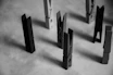 Several clothespins stand upright on a textured surface. The scene is captured in black and white, creating a minimalist and abstract arrangement of shapes and shadows.