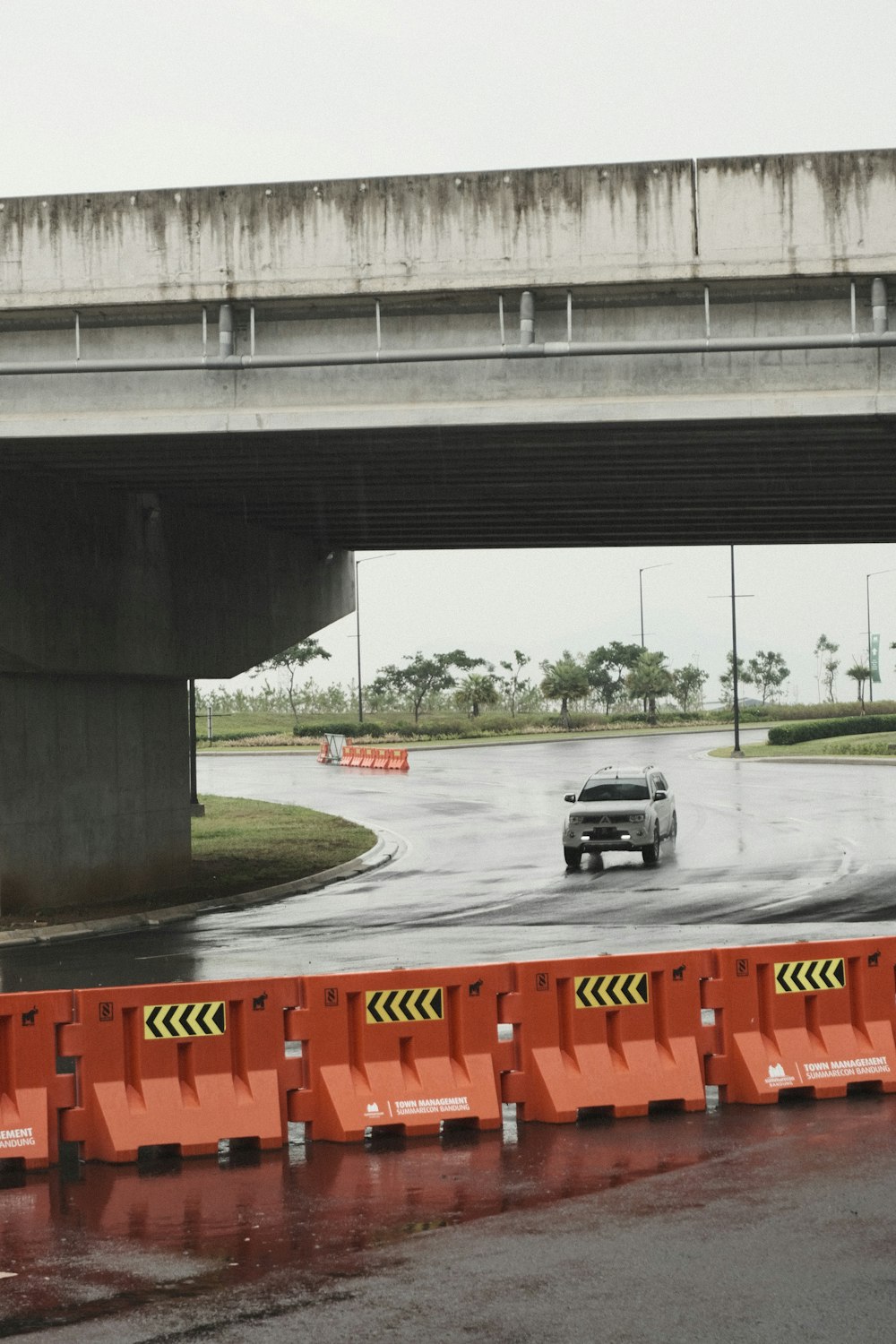 a car driving down a wet road under a bridge