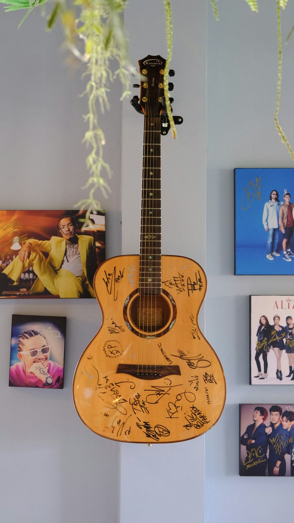 a guitar hanging from a wall with pictures on it