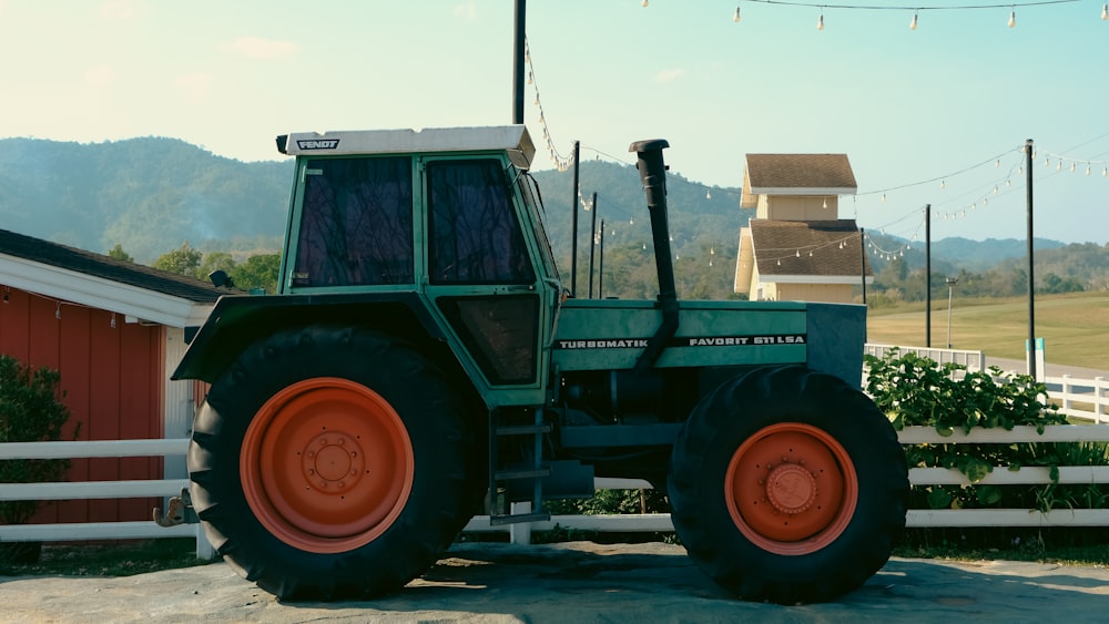 a green tractor parked in front of a red barn