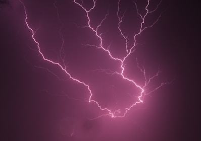 A close-up of a lightning bolt outlined in red softly glowing against a deep red background.