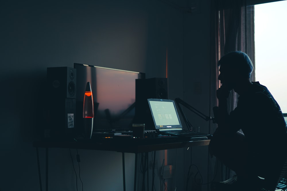 a man sitting in front of a computer in a dark room