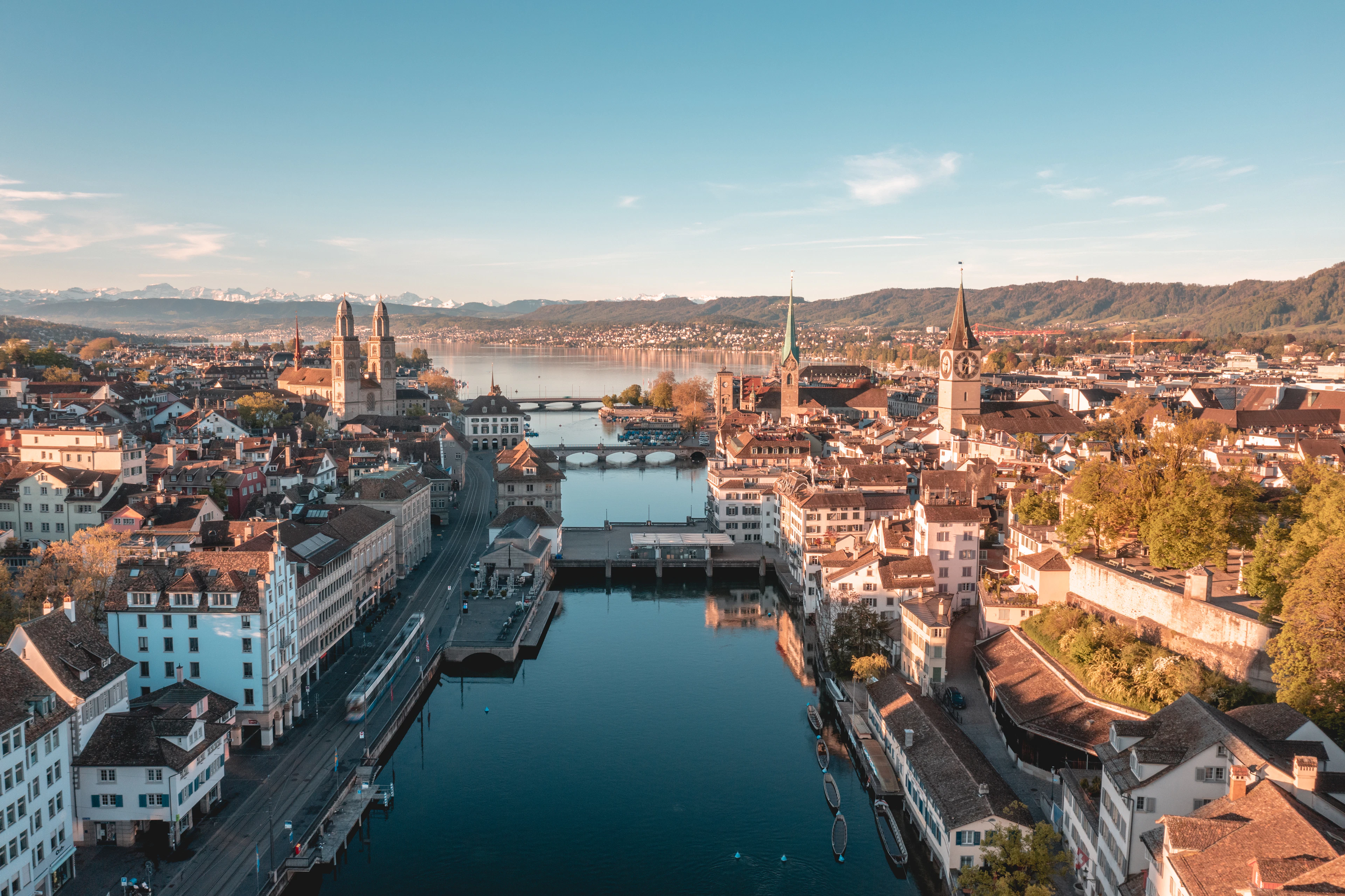 Aerial view down the Limmat as it runs through Zurich's old town, the twin towers of the Grossmuenster and other church spires on both banks and the snow-capped Alps on the horizon.