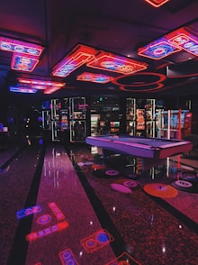 a room with a pool table and neon lights