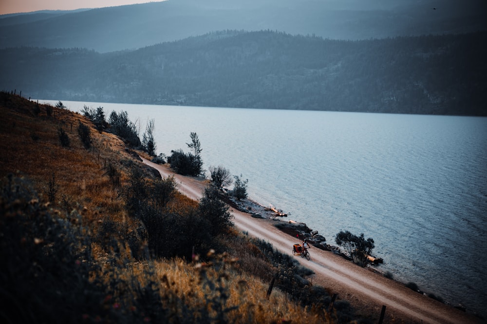 a car driving down a road next to a body of water