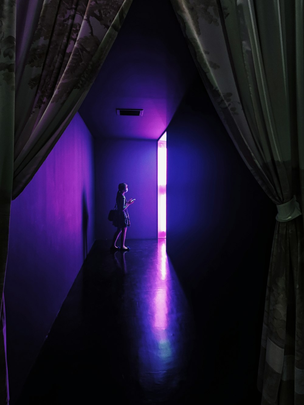 a person standing in a dark room with a purple light