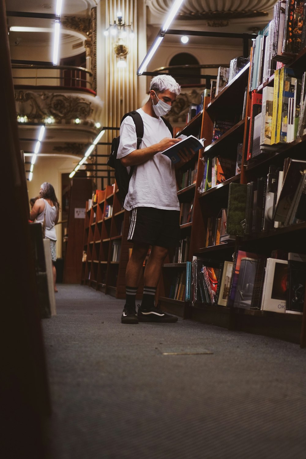 a man standing in a library reading a book