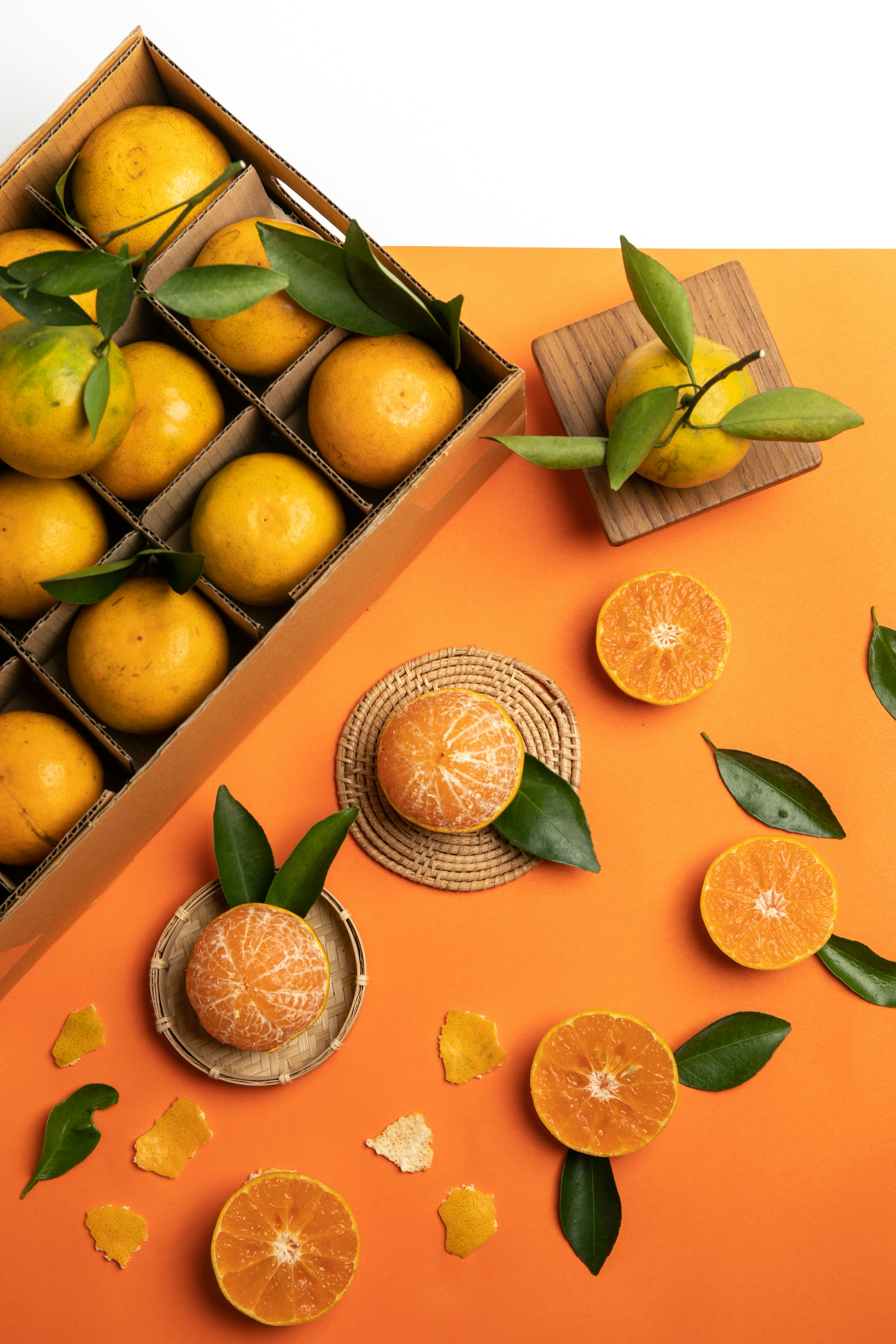 a box filled with oranges next to a bunch of leaves