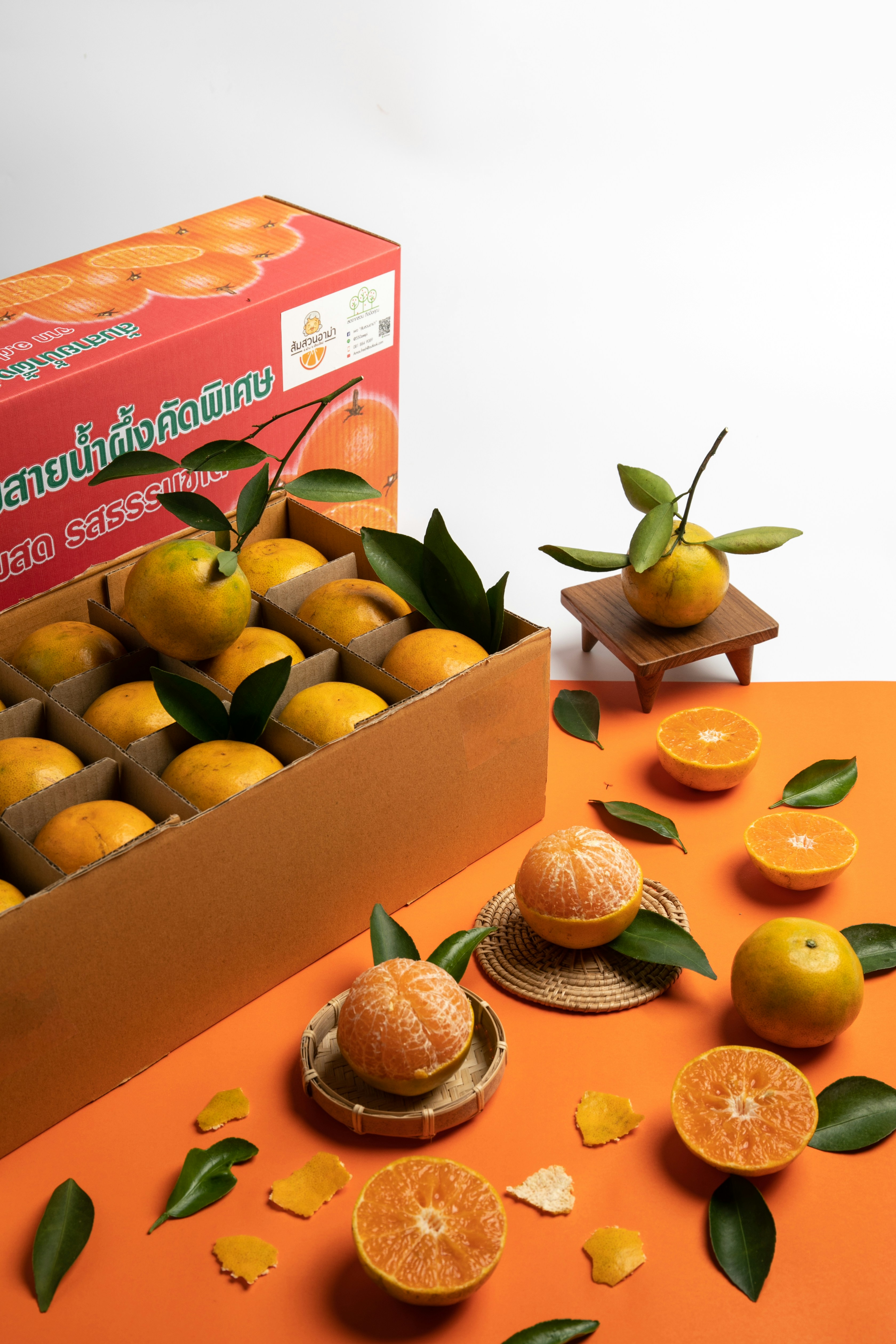a box of oranges with leaves on a table