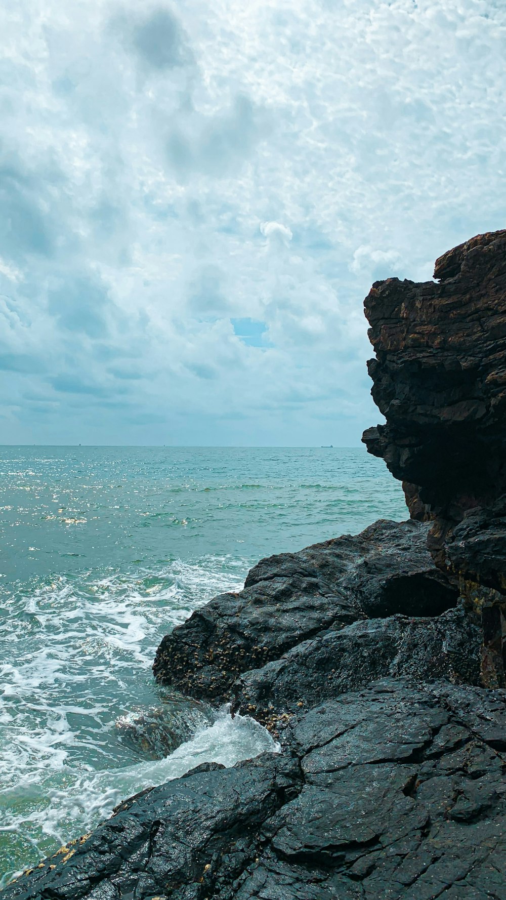 a person sitting on a rock near the ocean