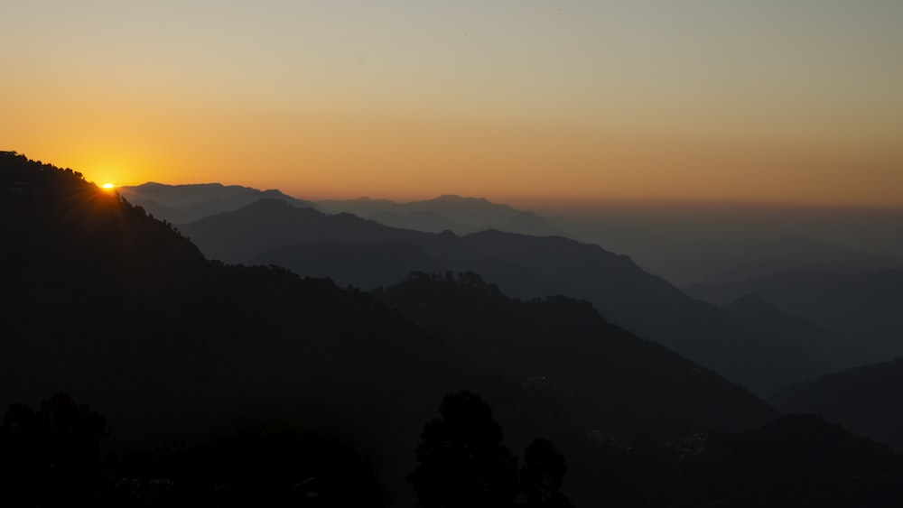 the sun is setting over a mountain range