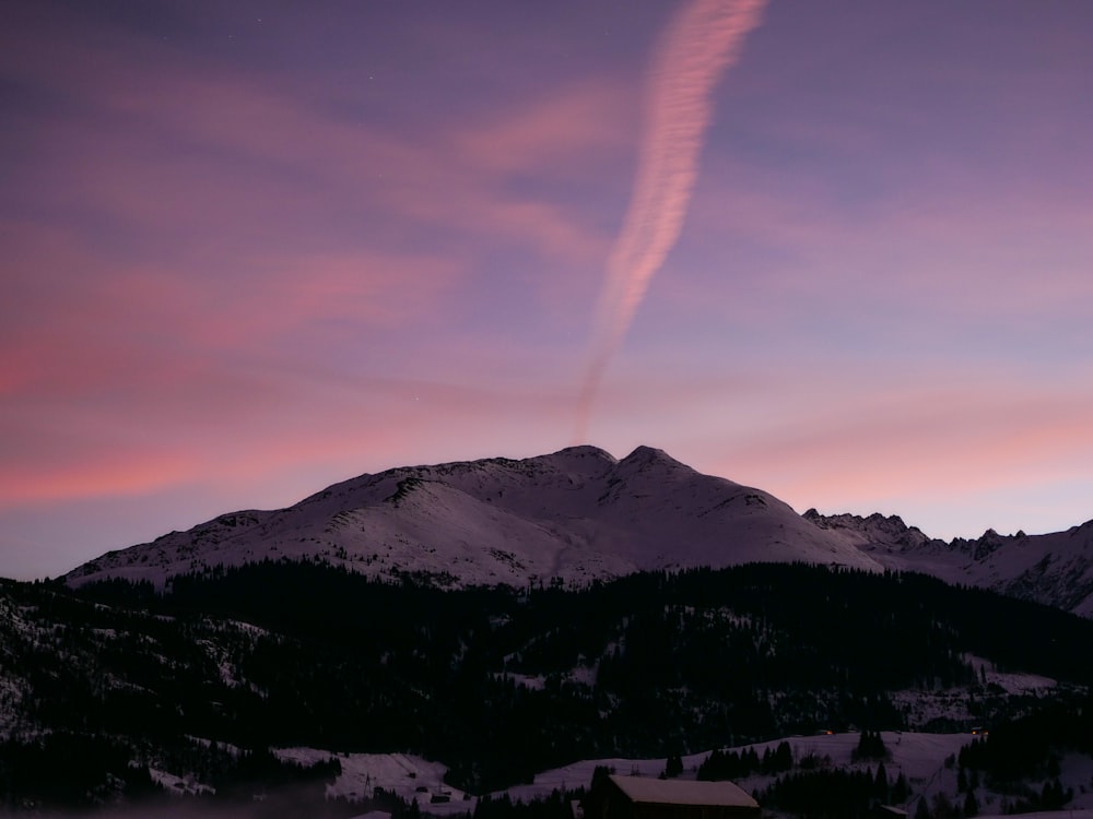 a purple sky with a contrail in the distance