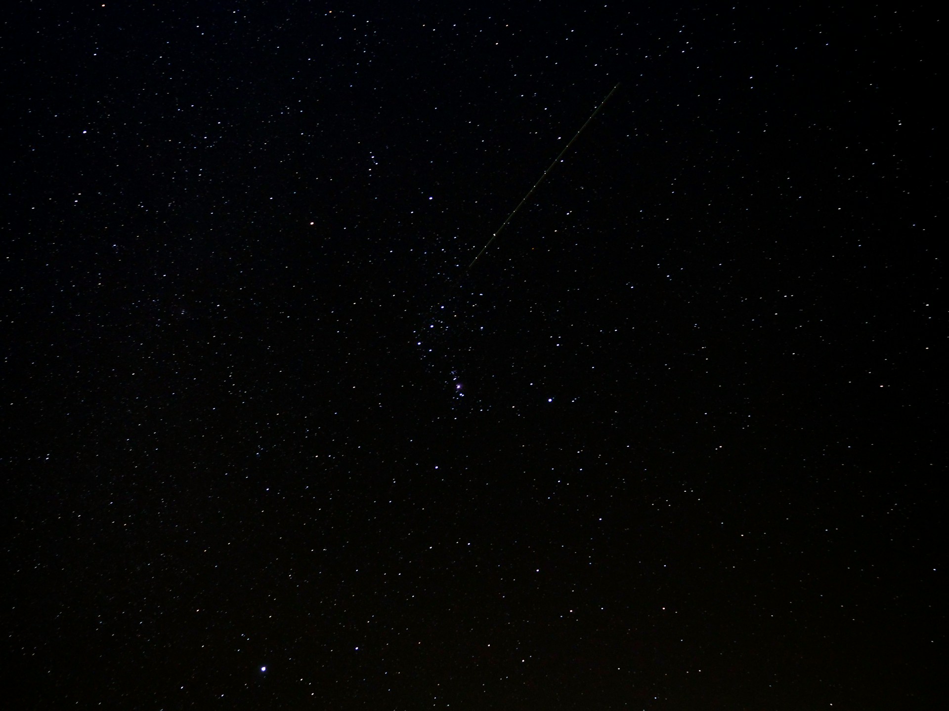 a night sky with stars and a plane in the distance