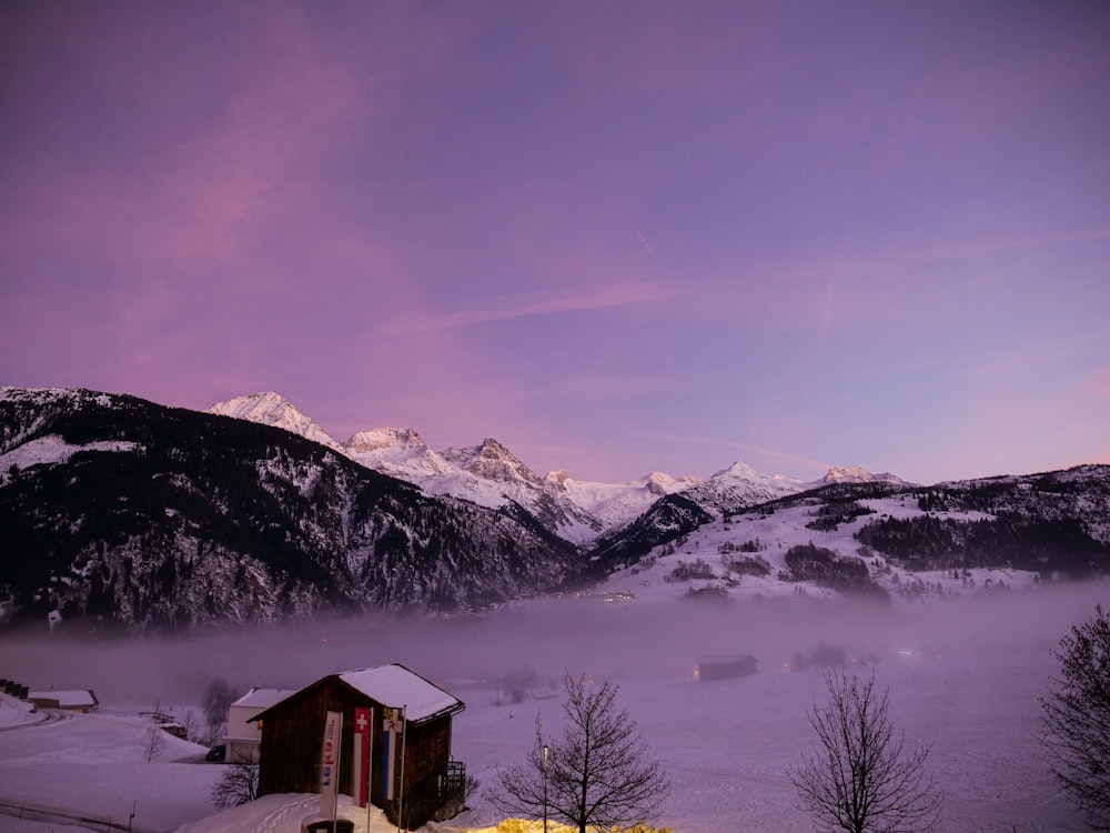 a snow covered mountain with a house in the foreground