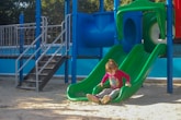 a little girl sitting on a slide in a playground