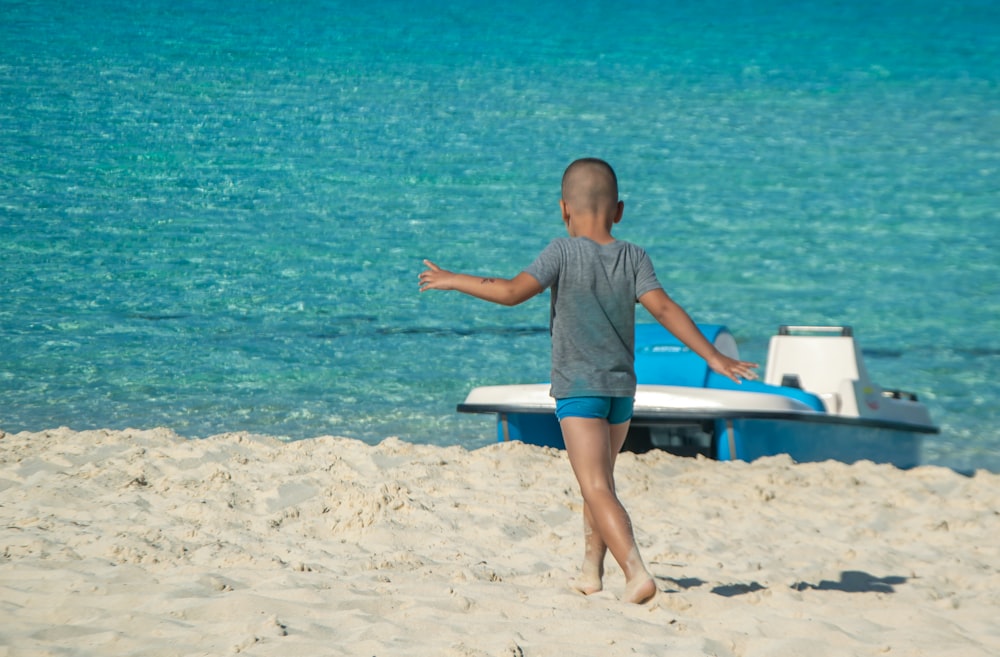 a young boy on a beach throwing a frisbee