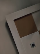 Geometric patterns composed of intersecting rectangles, with a square button or fixture at the bottom right corner. The surfaces exhibit a smooth texture with contrasting shades.