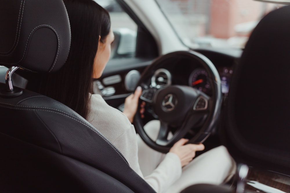 a woman sitting in a car holding a steering wheel