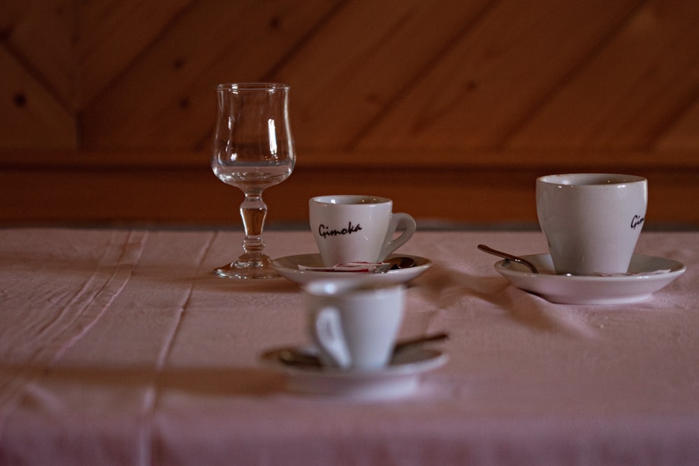 a table topped with white cups and saucers