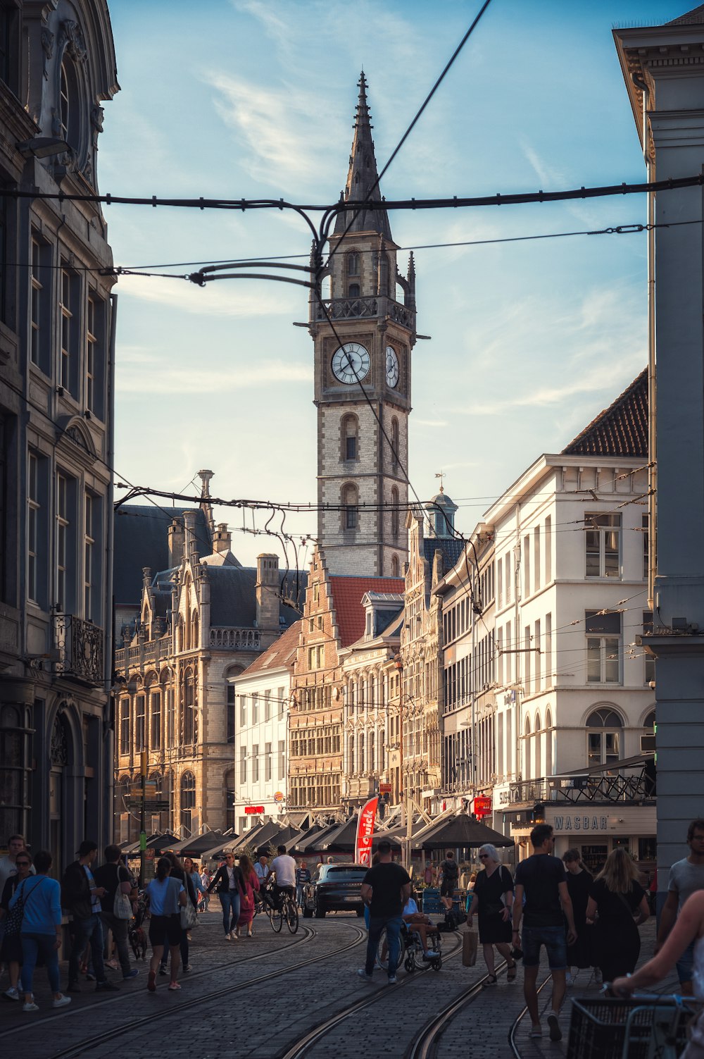 a group of people walking down a street next to tall buildings