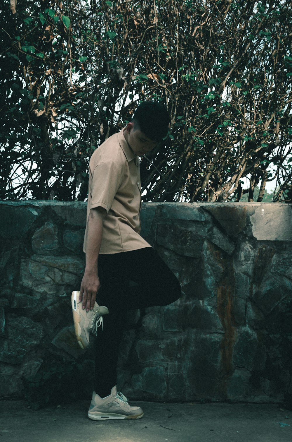 a man standing next to a stone wall