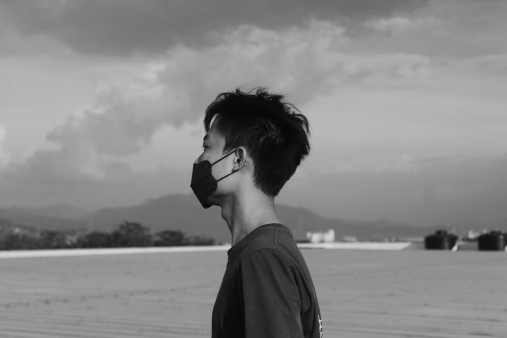 a man wearing a face mask standing on a beach