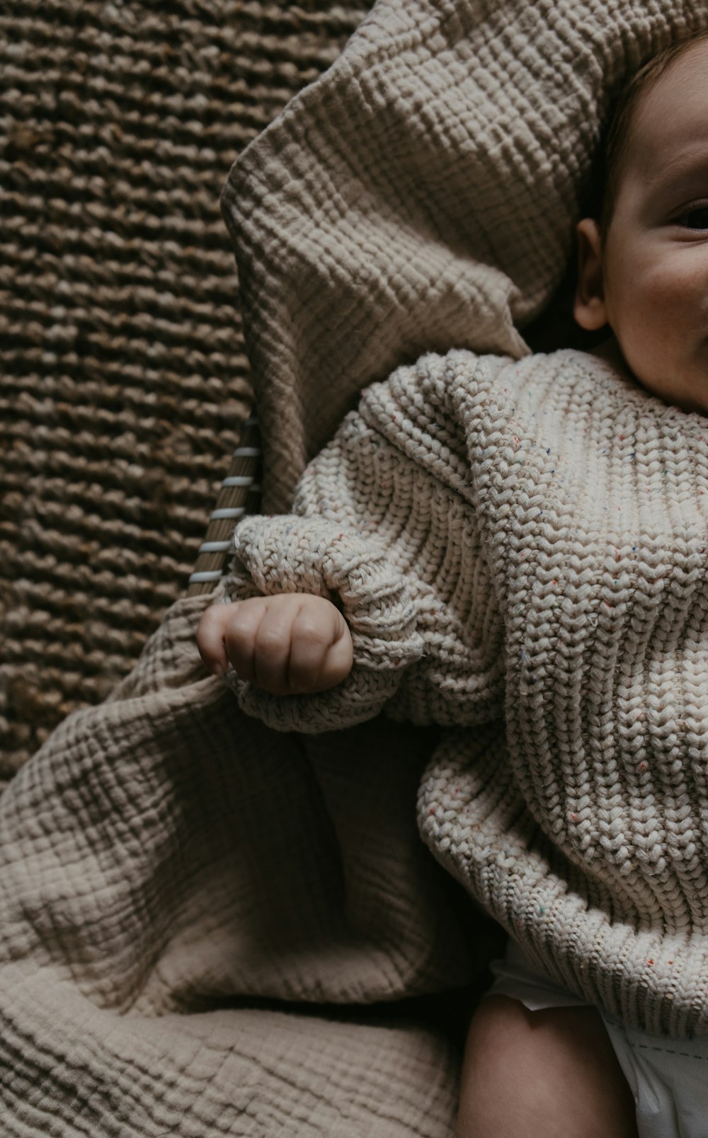 a baby wrapped in a blanket on a couch