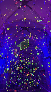 A vibrant neon-colored point cloud of an industrial building interior captured with SLAM laser scanning technology.
