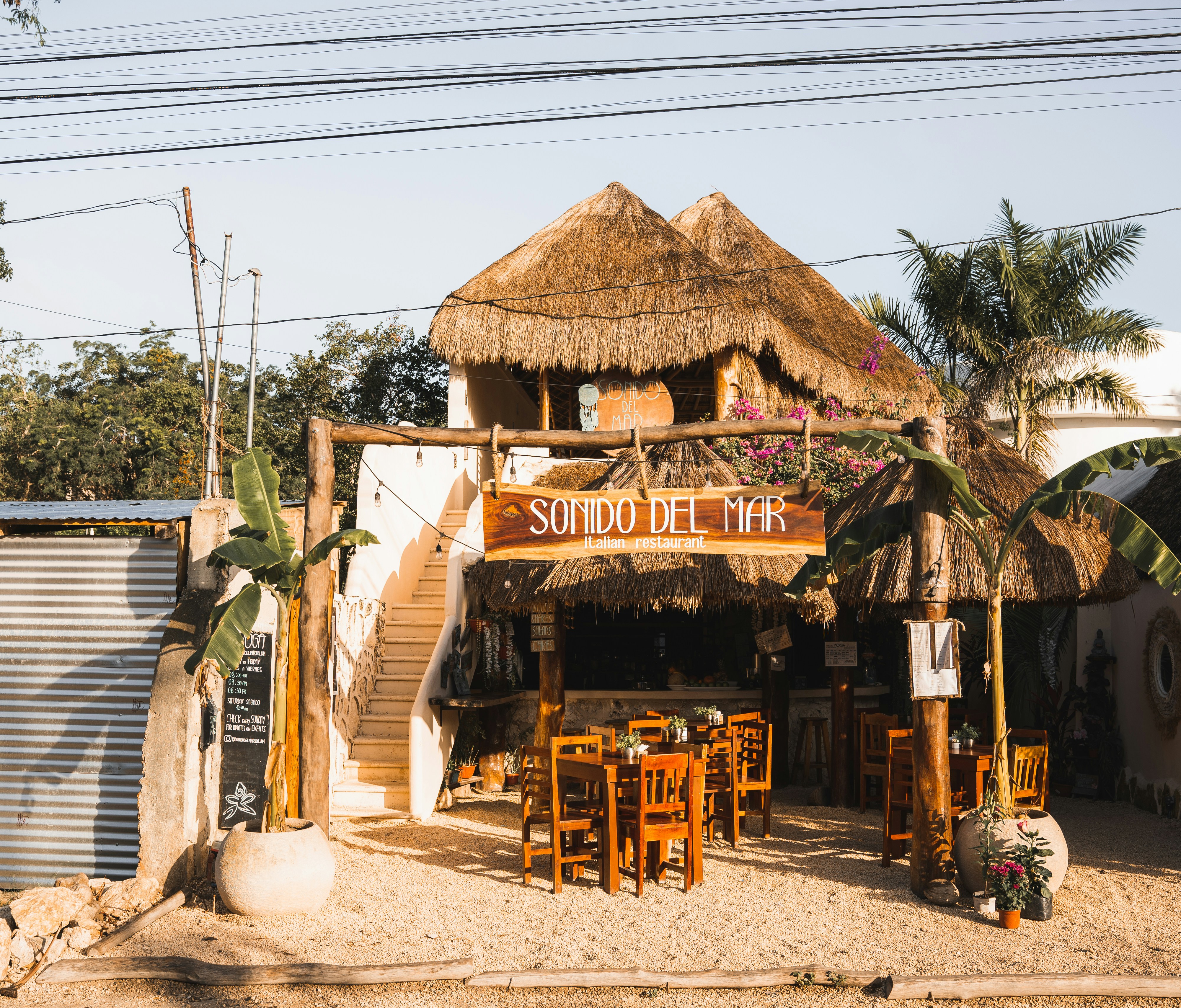 a tiki hut with a thatched roof and tables and chairs