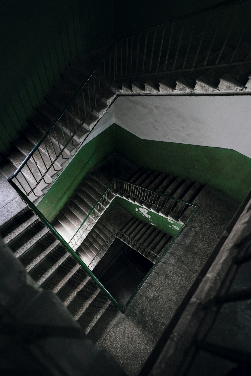 a staircase with a green handrail and a white wall