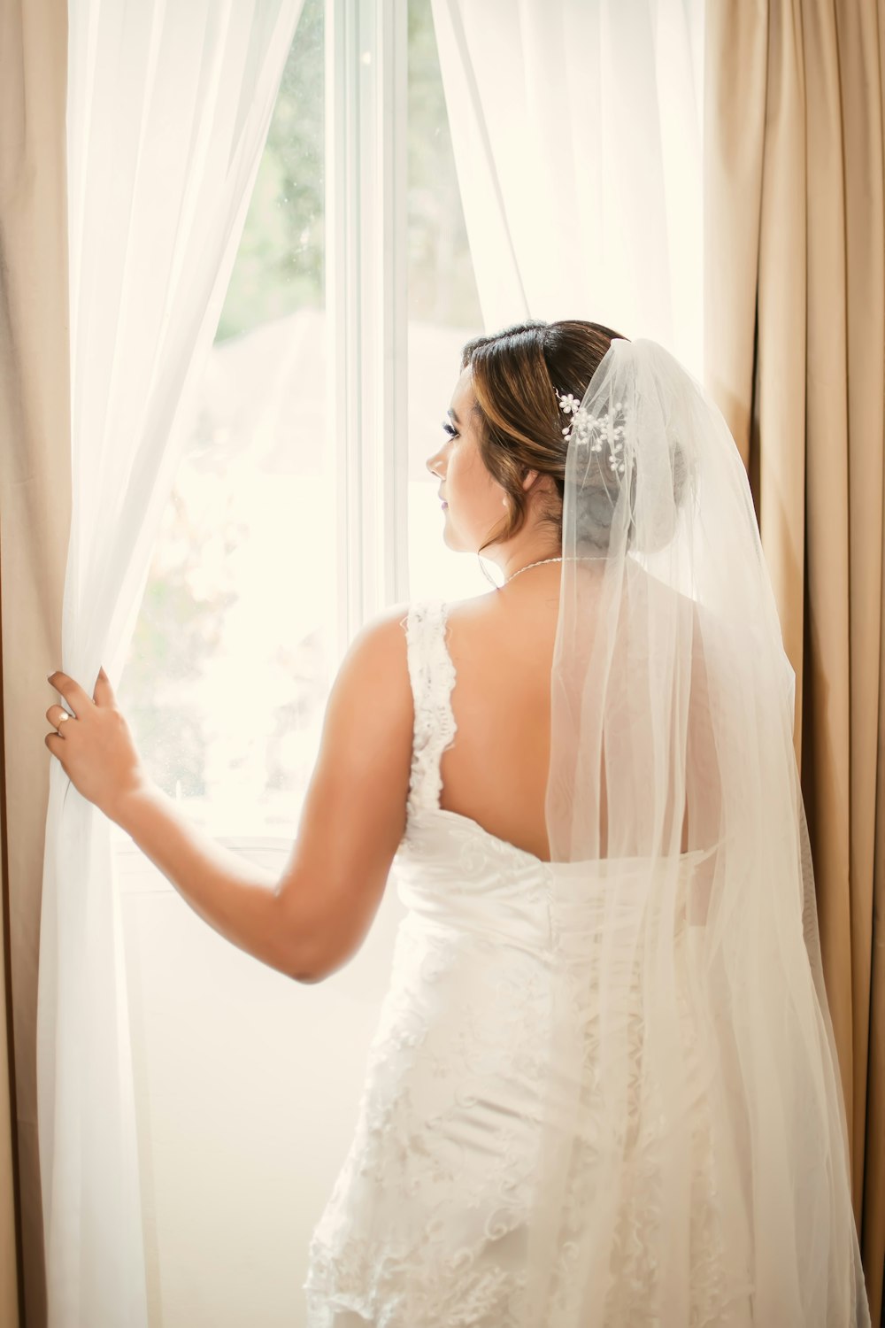 a woman in a wedding dress looking out a window