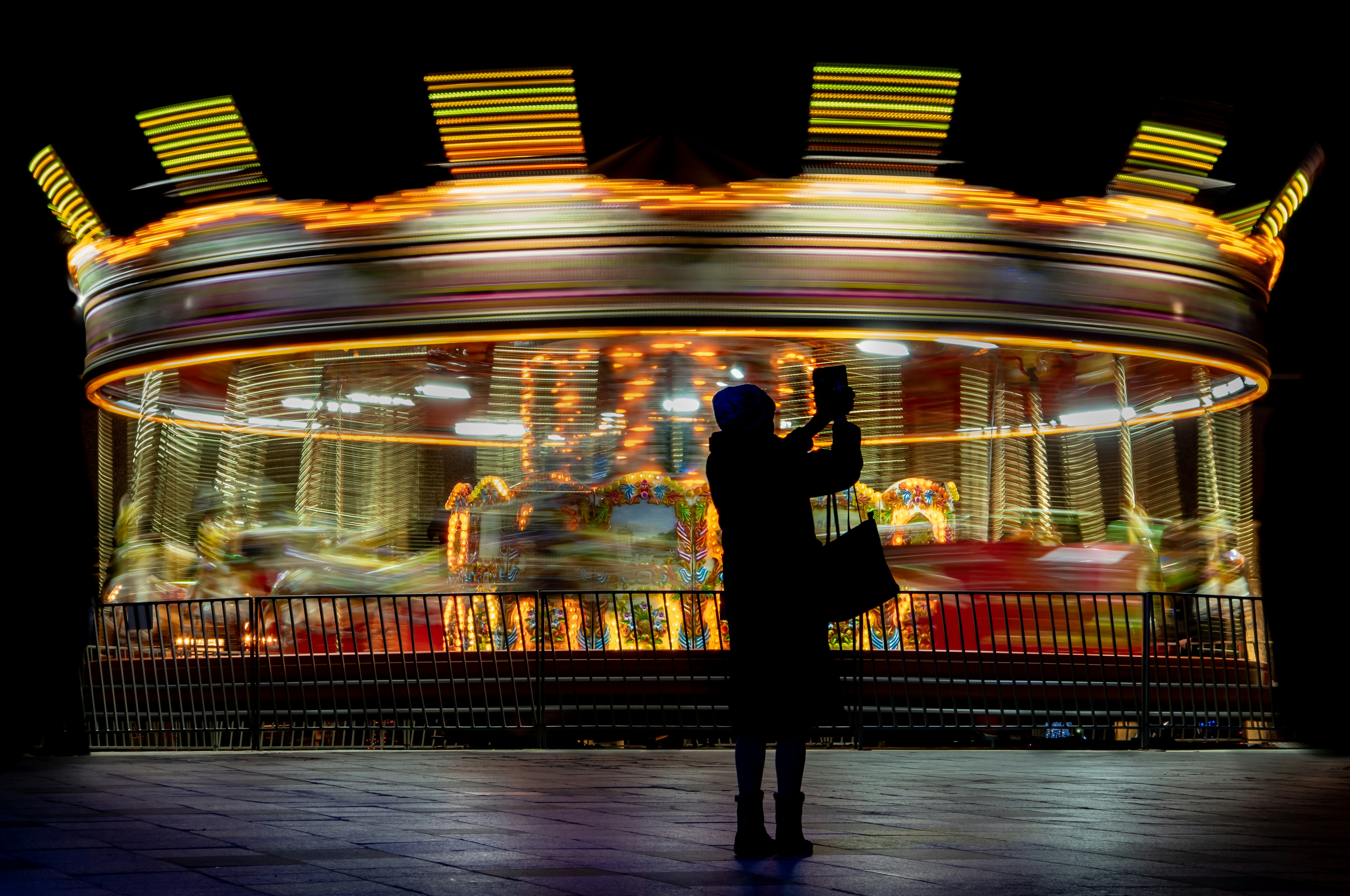 A person taking a picture of a carousel at night