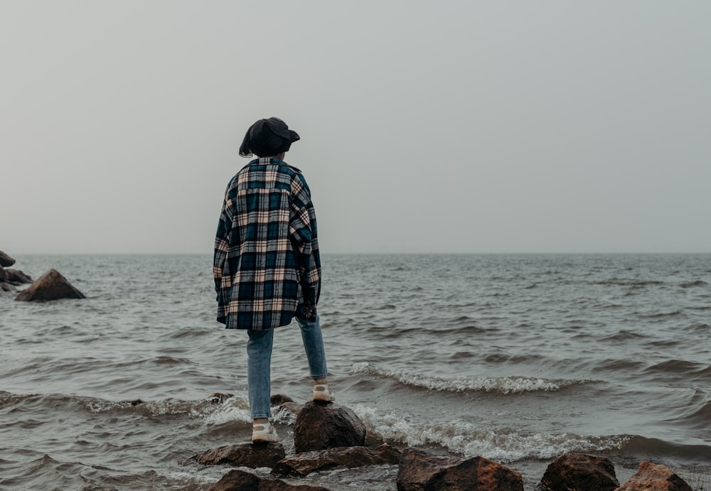 Una persona parada en rocas cerca del océano