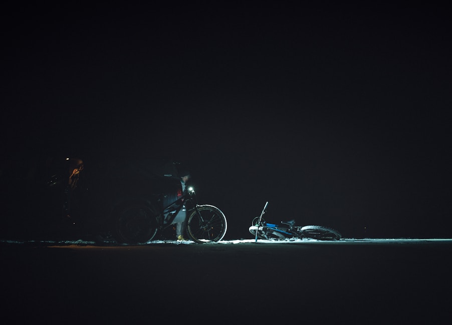 a man standing next to a bike in the dark