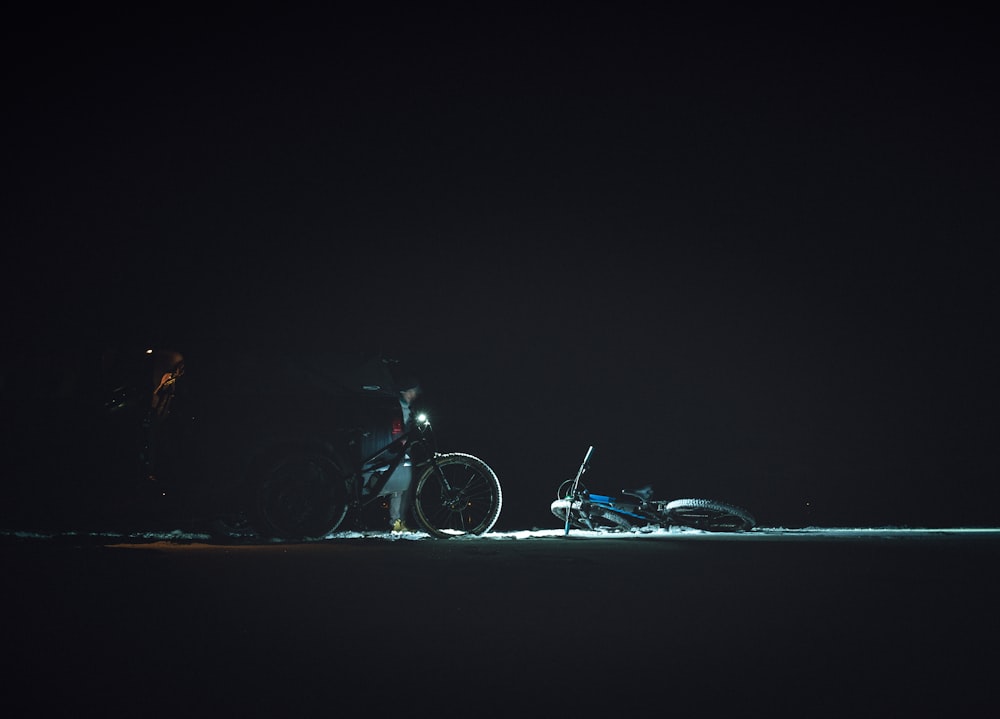 a man standing next to a bike in the dark
