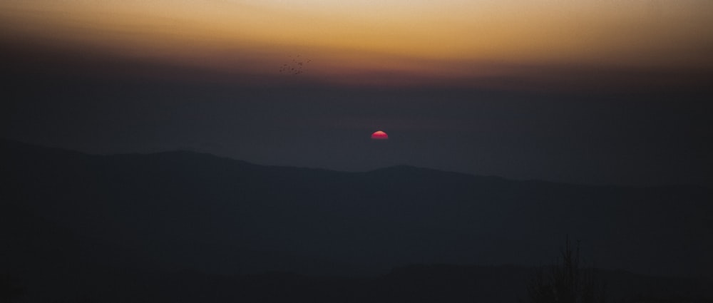 the sun is setting over a mountain range