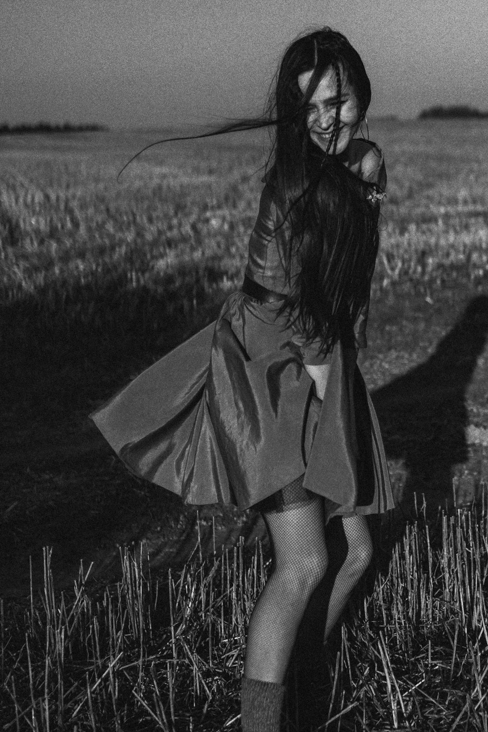 a woman standing in a field with her hair blowing in the wind