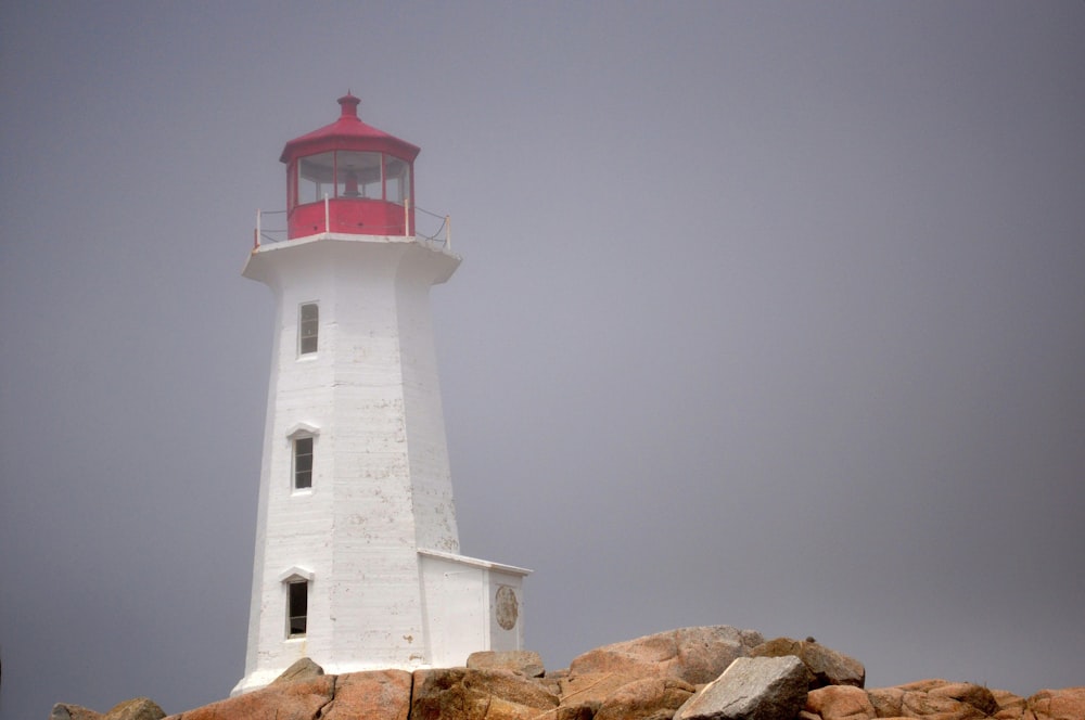 a red and white lighthouse on a rocky shore