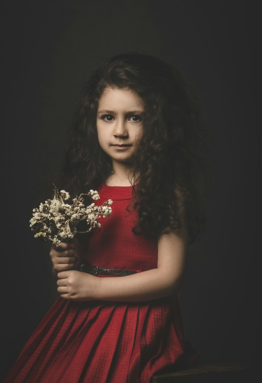 a young girl in a red dress holding a bouquet of flowers