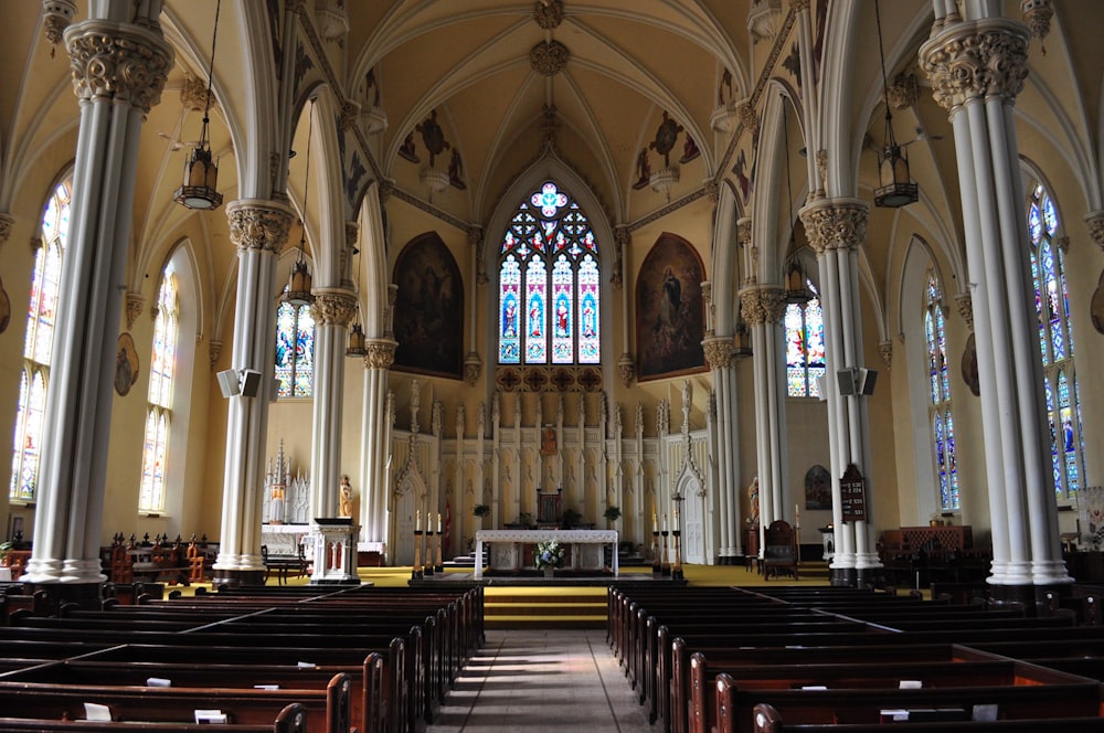 das Innere einer Kirche mit Bänken und Buntglasfenstern