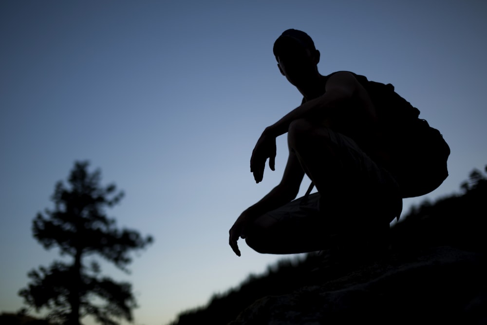 a silhouette of a person sitting on a rock