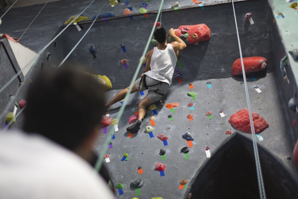 a man climbing up the side of a climbing wall