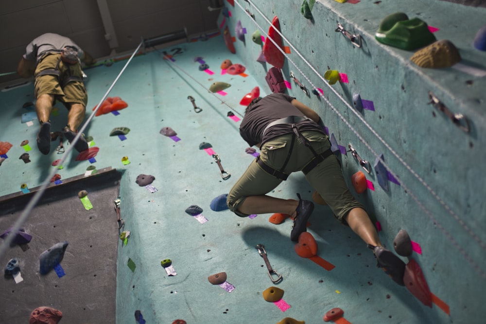 two climbers climbing up the side of a climbing wall