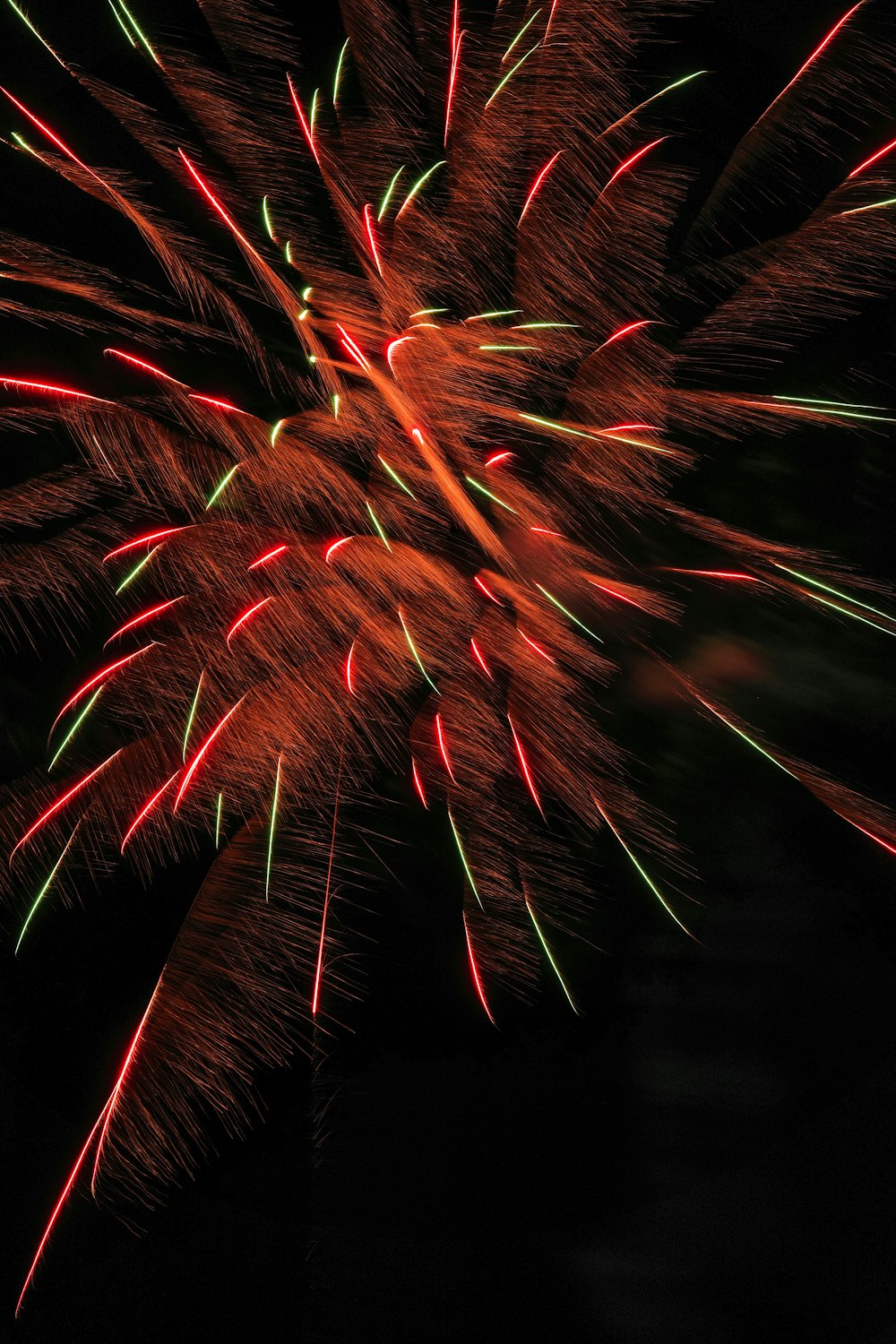a red and green firework in the night sky